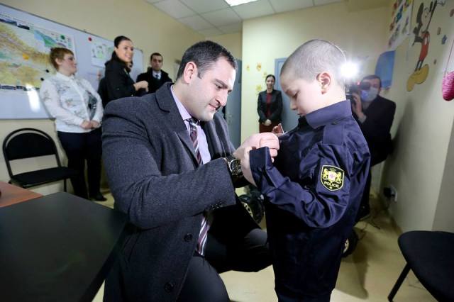 The Interior Minister, Alexander Chikaidze, presents a specially tailored patrol police uniform to one of the boys
