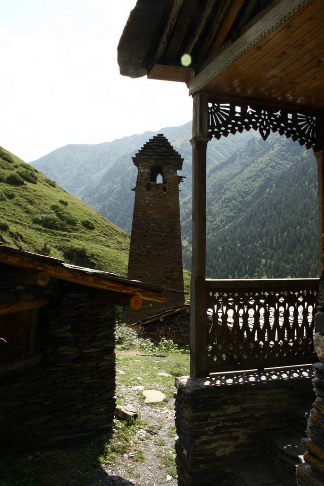 A fortified tower viewed from the balcony of a traditional house.