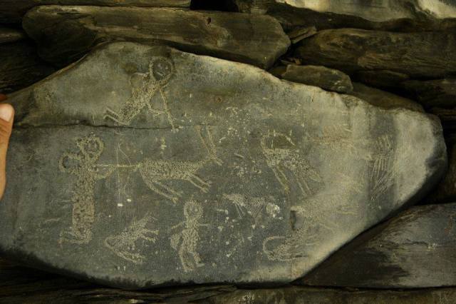 An old carving depicting a hunting scene on a stone forming part of a wall.