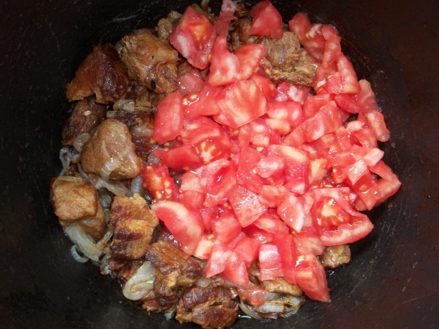 Adding tomatoes to barbecued pork and onions